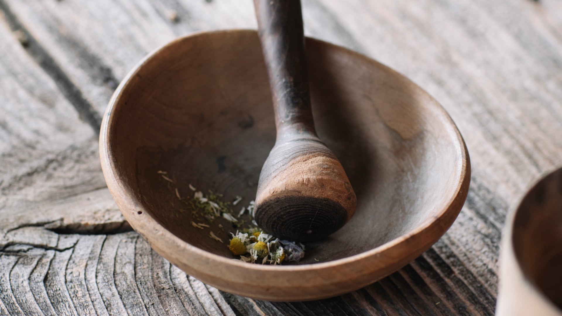 Wooden bowl with a pestle resting on a rustic wooden surface